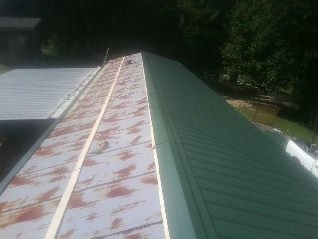 Old rusted panels beside newly installed green metal roofing — Wind Damage Roof Repair by Roofing Brothers in Cottondale